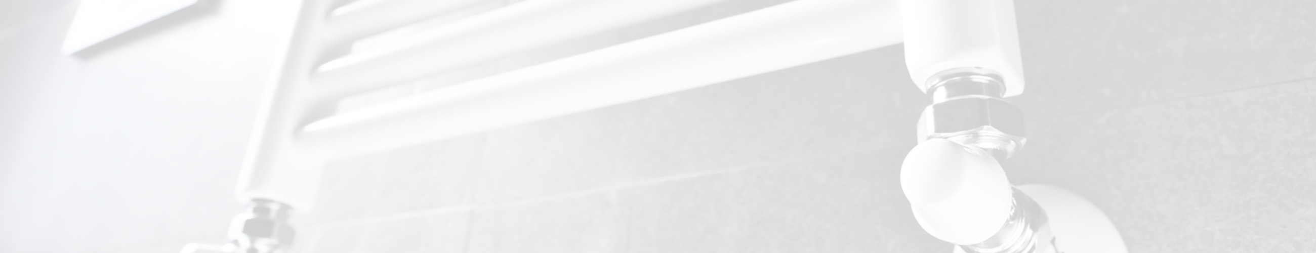 Ein seitlicher Ausschnitt eines weißen, wandmontierten Handtuchheizkörpers in einem modernen Badezimmer. Im Vordergrund ist das angeschlossene Ventil sichtbar, das in die Wand führt.  Über dem gesamten Bild liegt ein transparenter, weißlicher Schleier.